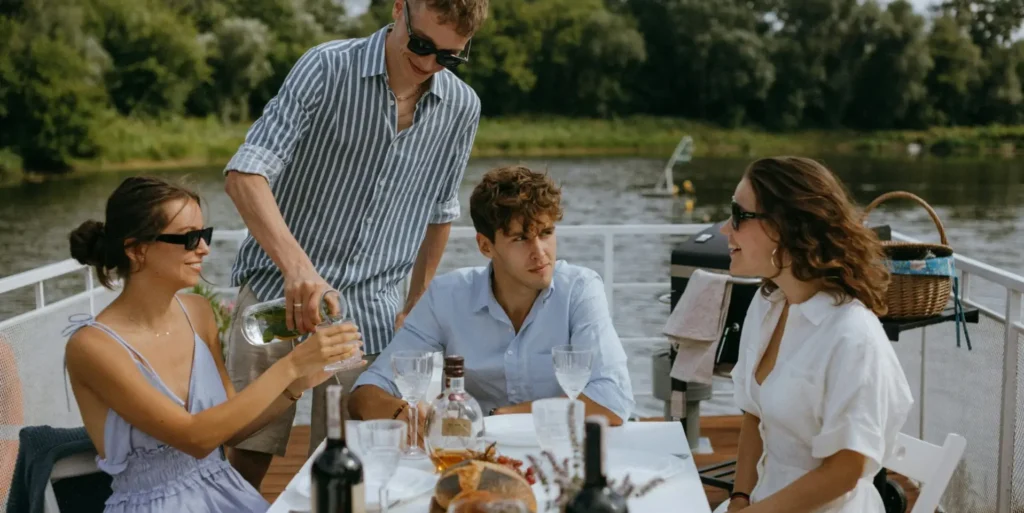 People wearing chique summer clothes sitting at a table with champaign and wine.